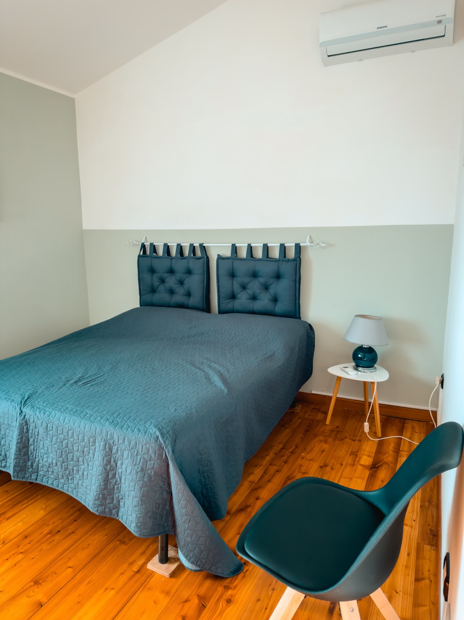 Double bedroom with a sage green wall and a wooden floor