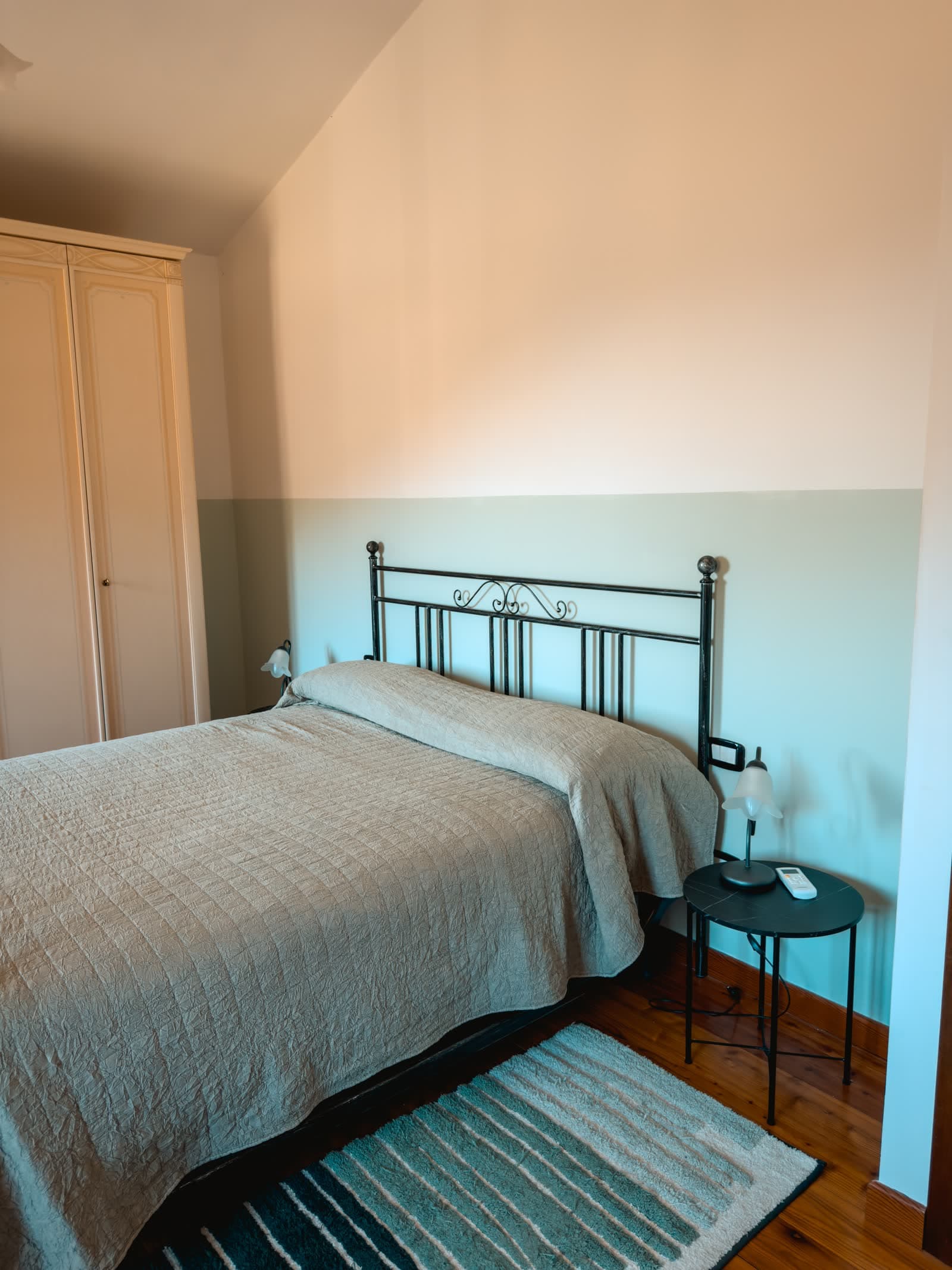 Bedroom with a wrought-iron bed, a wardrobe and a rug